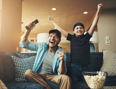 Televizyon, çocuk ve baba kanepede televizyon, abonelik ve birlikte maç izleme konusunda başarılılar. Evlat, insan ve patlamış mısır. Televizyon kumandalı. Kutlama, bağlanma ya da canlı yayın için..