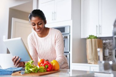 Tablet, malzemeler ve kadın mutfakta. İnternette sağlık, sağlık ve diyet yemeği tarifi var. Okuma, sebze ve Hintli insanlarda beslenme talimatları için dijital teknoloji kullanılıyor.