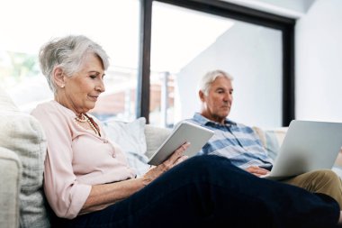 Laptop, tablet ve koltukta oturan yaşlı çift politik seçimler için internette haber okuyor. Rahatla, araştırma yap ve yaşlı kadın ve erkek bilgisayar ve dijital teknolojide evde oy kullanmak için kayıt ol