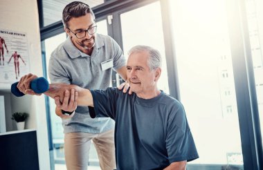 Kıdemli adam, fizyoterapist ve halterci ilerleme, iyileşme ve sağlığın dengesi için yardım edecek. Halk, sağlık ve rehabilitasyon destekli, özenli ve güçlü kas gücüyle klinikte..