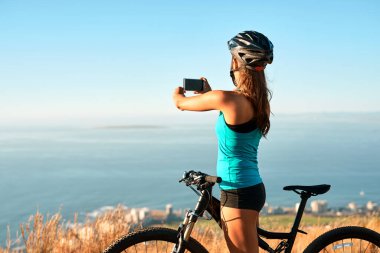 Kız, bisikletçi ve dışarıda seyahat blogu, hafıza ve sosyal medya paylaşımı ya da içerik oluşturulması için fotoğrafçılık yapıyor. Kadın, akıllı telefon ve dağ gezintisi, bisiklet ve tatilde macera için.