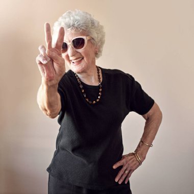 Moda, güneş gözlüğü ve duvarda havalı, havalı ve eşsiz eğlence estetiği tabelası olan büyük anne. Emeklilik, yaratıcı güzellik ve tasarımcı kadın gözlüklü yaşlı kadın model..