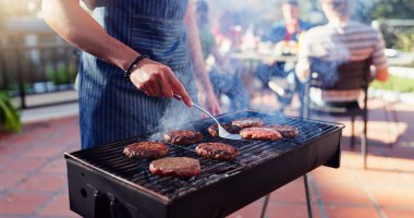 Barbekü, öğle yemeği ve arka bahçede hamburger yiyen bir adam buluşmada yemek, sosyal etkinlik ya da terasta parti. Hafta sonu evde barbekü, yemek ve erkek eti, köfte veya et pişirir.