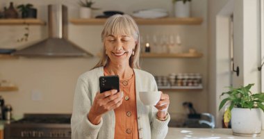 Ev, kahve ve internetteki telefonu olan yaşlı bir kadın, iletişim ve meşrubatla öğrenme. Ev, gülümseme ve internet medyası, bilgi ve sabah haberleri için akıllı telefonu olan yaşlı kişi.