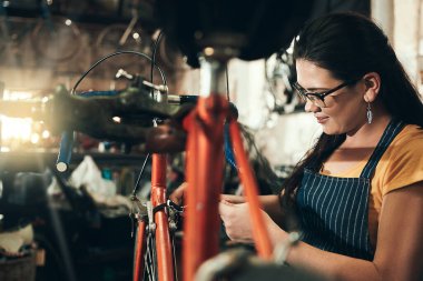 Kadın, bisiklet teknisyeni ve bakım, beceri ya da tamirhane alışverişi için denetimle tamir edin. Bisiklet tamircisi ya da mühendisi olan genç bir kadın, atölyede aletler ya da ekipmanlarla bisiklet üzerinde çalışıyor..