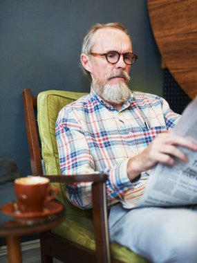 Gazete, kahve dükkanı ve borsa için iş bilgisi okuyan kıdemli bir adam. Cappuccino, gözlükler ve kafedeki gazetecilik makalesinde ekonomi manşetlerinin keyfini çıkaran yaşlı erkek.