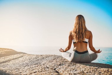 Sahilde, arkada ve Kaliforniya 'da yoga, sağlık ve ruhsal huzur için meditasyon yapan bir kadın. Zen, dişi yogi ve nilüfer çiçekli eller chakra için poz verir, rahatlayın ve açık hava modellemesiyle zihinsel sağlık.