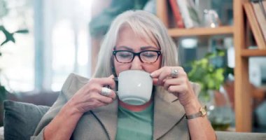 Ev, dinlenme ve kahveli yaşlı kadın, emeklilik ve oturma odasında latte ile mutluluk. Olgun kadın, daire ve emekli, fincanlı, cappuccino ve espresso ile sabah çayı, huzur ve huzur.