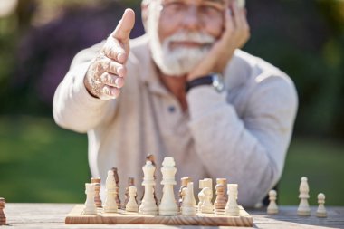 Kıdemli adam, oyuna hoş geldin için satranç ve tokalaşma, doğada strateji anlaşması. Erkek insan, el sıkışıyor ve açık havada yarışmada dost oyuncuyla el sıkışıyor ya da meydan okuyor..