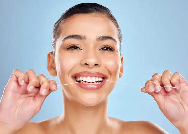 stock image Dental floss, hands of woman and portrait in studio for healthy gums, teeth whitening or morning routine on blue background. Wellness, oral care and model for fresh breath, plaque or mouth hygiene.