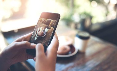 Fotoğrafçılık, sosyal medya ve şehirdeki durum güncellemesi için kafeteryadaki eller, akıllı telefon ve yiyecekler. Müritlerin blog, paylaşım ve çevrimiçi değerlendirmesi için restoranda kişi, nüfuz ve kahvaltı.