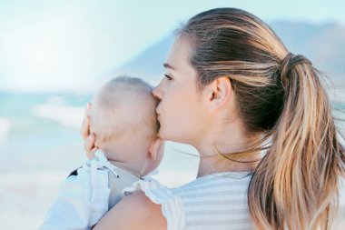 Öpücük, anne ve bebek birlikte sahilde bakım, sevgi ve destek için ya da doğada mutluluk için. Aile, çocuk ve kadın ya da anne çocukluk, gelişme ve macera için sabah konforlu.