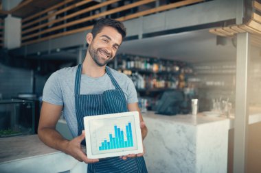 Tablet ekranlı, grafikli, karlı ya da kafede satış gelirli portre ve restoran. Erkek garson, barmen ya da çizelgeye, istatistiklere ya da kapalı mekândaki teknolojiye gülümseyen iş sahibi..