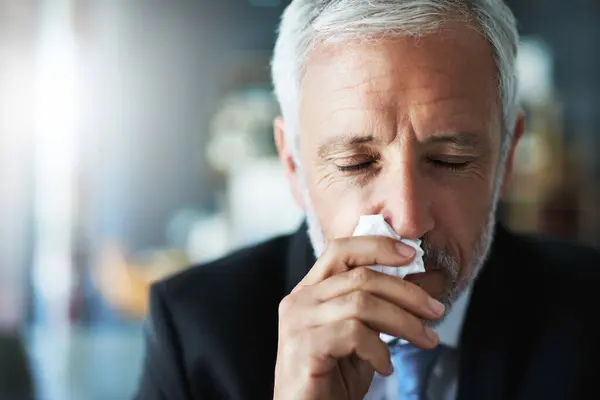 stock image Employee, sneeze and man with tissue, virus and disease with burnout, flu season and cold in workplace. Mature person, agent and lawyer with bacteria, blowing nose and sick with allergy or fever.