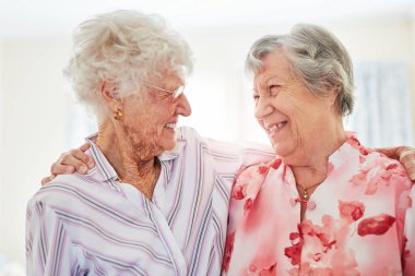 Arkadaşlar, yaşlı kadınlar ve evde sarılmak, eğlenmek ve eğlenmek için gülümsemek. Emeklilik, emeklilik ve huzur için huzurevine gidip dinlenmek için bağlanmaktan mutlu olmak..