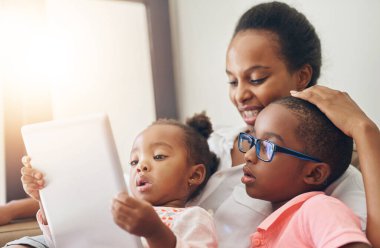 Anne, çocuklar ve dijital eğitimle birlikte öğrenme, büyüme ve gelişim için tabletleri olan ev. Kadın, genç insanlar, evdeki koltukta bilgi kitabı, çocuklarla kaynaşan anneler..