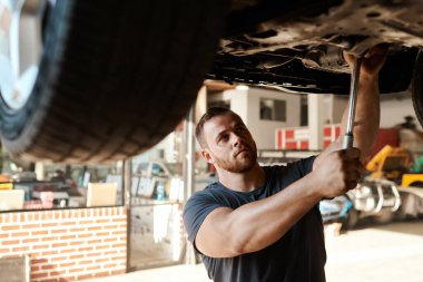 Tamir ve teftiş için atölyedeki tamirci, tamirci ve araç gereçler. Yol yapımcısı, tamirci ve garajda performans, ulaşım ve güvenlik için test lastiği üzerinde çalışıyor..