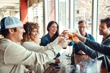 Şerefe, bira ve New York 'un şehir barındaki doğum günü kutlamasında restorandaki arkadaşlar. Mutluluğa gülümseyen ve yaz yemeğinde alkollü içeceklerle bir araya gelen bir grup insan..