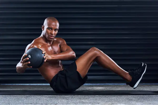 stock image Black man, medicine ball and exercise in gym, fitness and abdomen workout for strong muscle. Male person, athlete and equipment for training sports, russian twist and crunches practice on floor.