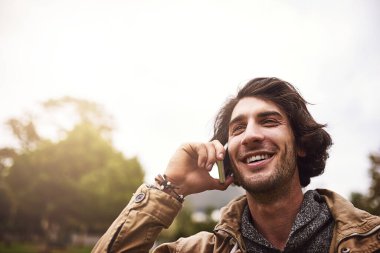 Açık hava, park ve telefon görüşmesi yapan mutlu bir adam. Gülmek, iletişim kurmak ve temasla dedikodu yapmak için. İspanya 'da doğa, erkek ve akıllı telefon sohbet etmek, düşünmek ve sohbet etmek için gülümseme ile bağlantı kurmak için..