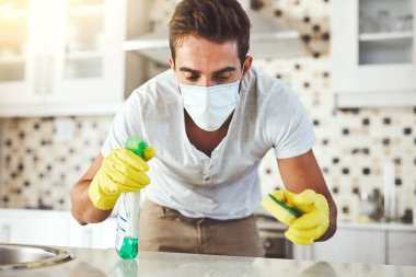 Evdeki temizlik için sünger ve sprey, dezenfekte ve kimyasallar. Erkek, yüz maskesi ve temizlik için toz, bakteri ve sıvı temizleme hizmetleri.