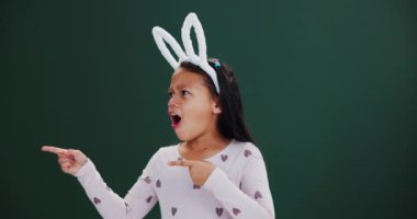 Şok, çocuk ve kız, Paskalya 'da tavşan kulaklı stüdyo modelinde elleri işaret ediyor. Tatil, sürpriz ve çocuk karanlık arka planda çılgın bilgiler gösterin. Şenlikli moda veya kostümlü haberler için yer açın..