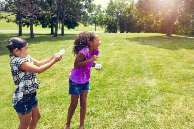 Su, balon ve kız çocuklar parkta oyun oynuyorlar, bağ kuruyorlar ve bahçede tatil yapıyorlar. Oyun, çocuklar ve çimenlerin üzerinde neşeli, enerjik ve arka bahçede yaz tatilinde su sıçratan mutlu arkadaşlar..