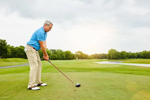 stock image Mature, man and swinging on field for golf or ball for improve balance, coordination and retirement leisure with relax. Golfer, club and play on lawn for physical activity, mobility and outdoor sport.