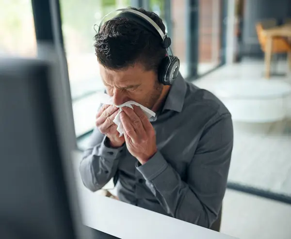 stock image Man, call center and tissue for nose by computer with consulting, sick or flu on voip. Agent, headphones and toilet paper, mucus and allergies for tech support, telemarketing and customer care at job.