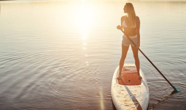 Göl, gün batımı ve güneş ışığı, su sporu ve turizm için nehirde tatil yapan bir kadın. Almanya 'da kadınlar için spor, yaz veya tatil, mayo veya macera için seyahat egzersizi.