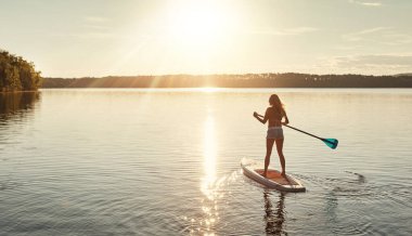 Göl, gün batımı ve dinlenmek için sörf tahtasında bir kadın, su sporları ve turizm için nehirde tatil. Almanya 'da kadınlar için güneş ışığı, yaz ve tatil, mayo ve macera için seyahat kondisyonu.