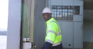 İnşaat işçisi, fabrikanın garaj kapısında sabah rutiniyle ve günün başlangıcıyla çalışan bir adam. Afrikalı mühendis, profesyonel ve atölye, depo veya çalışma alanında silindiri olan kişi.