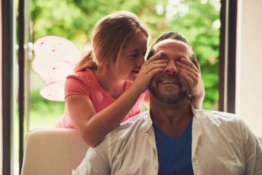 Home, father and child with peekaboo for play, laughing and bonding together with games. Family house, dad and daughter with connection, cover eyes and girl in living room with caring parent on sofa. clipart