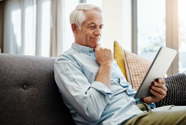 Kıdemli adam, tablet ve emeklilik e-posta, iletişim ve online haberleri okumak için evde. Yaşlılar, teknoloji ve dinlenme odasındaki kanepede fatura ödemesi, video ya da kitap okuma için dinlenme.