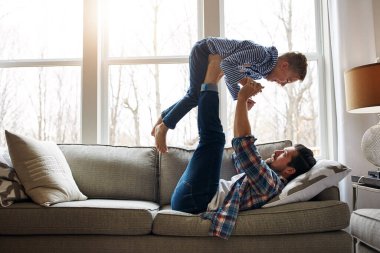 Baba, oğul ve destek, bağ kurmak için kaldırma, ilişki ya da oyun için birlikte. Baba, çocuk ve güçlü bacaklar kanepede oynamak ya da gelişmek için, aile evinde öğrenerek rahatlayın..