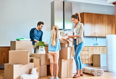 Taşınmak için yeni evde kutuları olan ebeveynler ve çocuklar oturma odasında emlak ya da emlak yatırımları. Aile, genç kız ve kadınla birlikte mutlu bir adam taşınma, yardım veya ipotek için.
