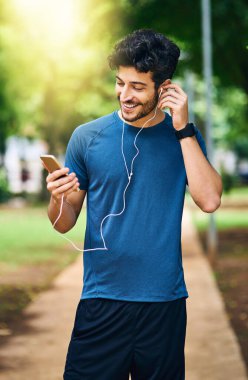 Kulaklıklar, fitness ve akıllı telefonlu adam, park ve motivasyon podcast ile mutluluk. Gülümse, cep telefonu, radyo ve internet üzerinden ses, canlı müzik ve spor için açık havada.