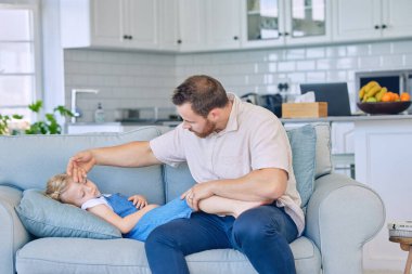 Çocuk, hasta ve baba oturma odasındaki kanepede hastalıklı ve gençlerin sağlık sorunları olan ateşi kontrol ediyor. Aile evinde uyuyan bir çocuğun gribi yüzünden stresi ve endişesi olan bir babaya sağlık, destek ve bakıcılık..