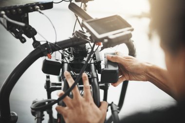 Fotoğrafçılık, prodüksiyon ve medya için objektifi olan bir adamın elleri, kamera ve elleri. Sahne arkasında, sahne arkasında ve set çekim videolarında, belgeselde ve filmde dengeleyici ekipmanı olan kişi.