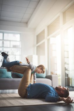 Uçak, oyun oynamak ve evde çocuklu mutlu bir baba, ilişki ve oturma odasında rahatlamak için. Aile, oyuncu ve genç bir çocukla baba. Uçmak, denge kurmak ve yerde oyun oynamak için eğleniyorlar..