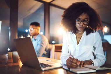 Dizüstü bilgisayar, defter ve kadın gece ofiste varlık yönetimi araştırmaları için son teslim tarihiyle birlikte. Bilgisayar, yazı ve Afrikalı kadın sigortacı müşteri zamanlaması finansal yatırım analizi ile.