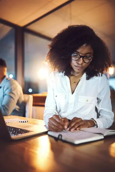 stock image Laptop, notebook and business woman at night in office with research for wealth management report with deadline. Computer, writing and African female actuary working overtime on financial investment