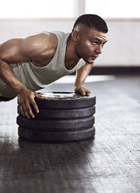 Ağırlıklar, plakalar ve vücut geliştirme egzersizi için spor salonunda şınav çeken bir adam. Enerji, zindelik ve spor merkezindeki güç için kol egzersizi ekipmanlarıyla erkek sporcu.