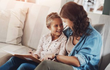 Anne, kız ve kitap kanepede yazma, öğrenme ve aile evinde kaynaşma, yardım ve bakımla mutlu. Eğitimli kadın, anne ve çocuk Münih 'te ev ödevleriyle ilgili danışmanlık, çizim ve rehberlik.