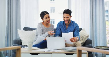 Finans, dizüstü bilgisayar ve kağıt. Banka ödemesi için evin oturma odasındaki kanepede bir çift oturuyor. Sigorta, ipotek veya vergileri gözden geçirmek için dairede kadın ve erkeklerin bulunduğu muhasebe, bilgisayar veya belgeler.