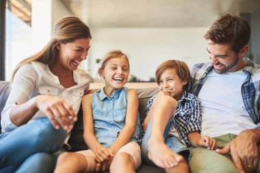 Mutlu bir aile, çocuklar ve kanepede sevgiyle gülmek, sağlıklı bir ilişki ve evde şakayla kaynaşmak. Çocuklar, aileler ve güvenlikli komedi hikayeleri için gülümseyin, sakin bir hafta sonu ve birlikte dinlenin..