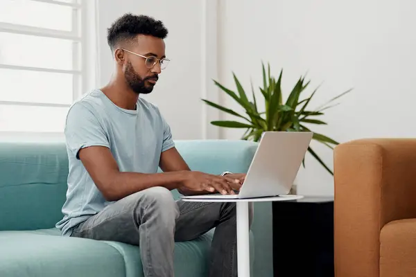 stock image Computer, remote work and black man typing in home for research, project or online report. Freelancer, laptop or journalist on sofa for writing article, story or reading email on internet in lounge.