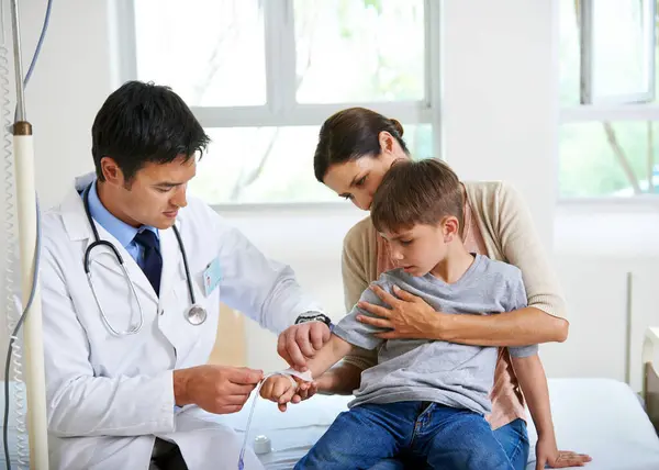 stock image Child, doctor and iv drip for healthcare in hospital of medicine treatment, hydrate and nutrition healing. Mom, pediatrician and patient with infusion procedure for emergency solution of wellness.