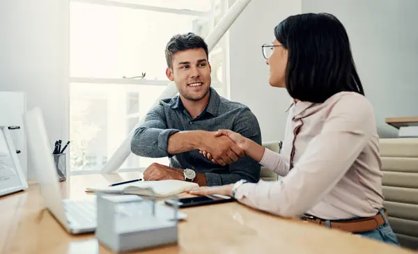 Stock image Handshake, creative and employees with smile, laptop and happy for collaboration in office and web designer. Meeting, holding hands and partnership for project, man and woman with conversation.