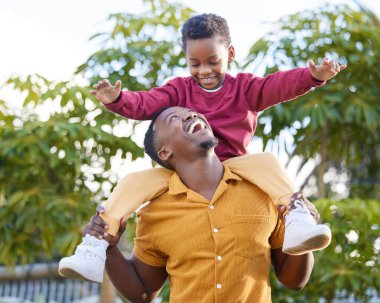 Baba, gülümse ve siyah adam sırtına al evlat, eğlence ve neşe açık hava parkında birbirine bağlanıyor. Aile, çocuk sevgisi ve Afrikalı insanları oynamak, çocuk ve baba bahçede oyun oynayan çocuğu taşımak.